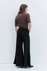 Jeans de tiro alto en color negro, con diseño de corte acampanado y paneles godet que aportan amplitud en el bajo. Presenta costuras visibles y cierre frontal con botón y cremallera.