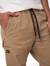 Pantalon Caterpillar de twill elastizado en color beige, con bolsillos laterales tipo utilitario, detalle de etiqueta con logo de la marca y corte ajustado.