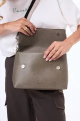 Bandolera de cuero sintético negro con solapa frontal y herrajes plateados. Incluye una correa ajustable y extraíble con diseño de rayas en tonos beige y negro.
