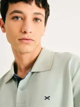 Chomba de manga corta color negro con cuello y tapeta interior en color gris claro. Presenta un pequeño bordado en el pecho y detalles de ribete en gris en el cuello y las mangas.