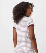 Blusa de pijama de cuello redondo y manga corta, confeccionada en tejido peach touch color blanco con estampado geométrico de corazones en tono bordó. Cuenta con detalles de encaje en los puños y un pequeño moño decorativo en el escote.
