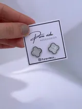 Aros tipo caravanas con diseño de trébol de cuatro hojas en color blanco con efecto marmolado y borde metálico.