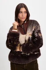 Buzo de tejido de punto jacquard con textura de pelo, con diseño estampado de paisaje de bosque. Presenta cuello alto con cierre frontal parcial, puños acanalados en tonos marrón y crema, y un parche decorativo en la manga.