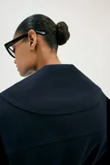 Chaqueta estilo trench corta color azul marino confeccionada con lino. Cuenta con cuello solapa, manga larga con trabilla, bolsillos delanteros de vivo y cierre frontal con lazada ajustable en la cintura.