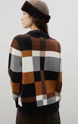 Sweater de punto con diseño jacquard a cuadros en tonos azul, marrón, crema y negro. Presenta cuello redondo, puños y ruedo acanalados, con un corte holgado y cómodo.