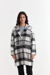Tapado de paño con diseño de cuadros en tonos negro, gris y blanco. Presenta solapas clásicas, cierre frontal con botones y bolsillos frontales aplicados.