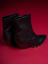 Botas negras de caña baja con punta fina y detalle de tachas plateadas en la suela.