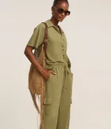 Pantalón largo verde militar de corte fluido, con cintura elástica, cordón de ajuste y bolsillos cargo en los laterales.