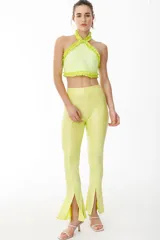 Pantalón tipo calza de tiro alto, color amarillo lima, con textura acanalada y aberturas frontales en el ruedo.