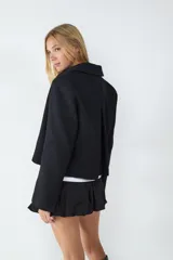 Campera corta negra con cierre frontal metálico, cuello camisero y mangas largas.