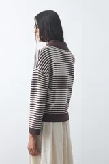 Sweater de punto a rayas horizontales en color bordó y celeste, con cuello polo y mangas largas con puños amplios. Presenta un diseño de calce relajado.