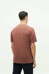 Remera marrón de manga corta con cuello redondo y estampado frontal con texto y flores.