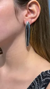 Caravana de diseño minimalista con forma de gota alargada en acabado metálico plateado pulido.