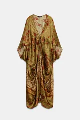 Vestido largo de seda, color verde oliva con estampado floral en tonos rojos y terracota. Presenta escote pico con ajuste fruncido en el delantero y mangas amplias tipo murciélago.
