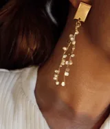 Aros colgantes dorados con base rectangular y múltiples hilos colgantes con pequeñas perlas blancas.