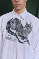 Camisa blanca de algodón con cuello clásico, manga larga con puños abotonados y estampado frontal de un animal similar a un zorro.