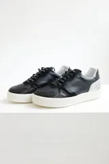 Zapatillas urbanas de cuero negro con cordones negros y suela blanca.
