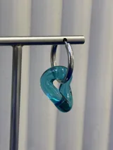 Aros colgantes compuestos por una argolla de plata 925 y un dije de vidrio soplado con forma orgánica irregular en color turquesa.