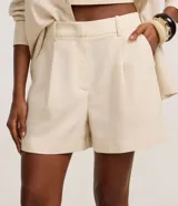 Short femenino color marrón oscuro, con trabillas en la cintura, pliegues frontales y solapa trasera.