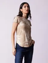 Remera color beige con estampado de hojas blancas, cuello redondo y mangas cortas.