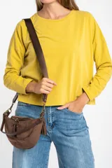 Remera oversize de manga larga color marrón, con cuello redondo y efecto de lavado. Presenta un pequeño bordado en forma de estrella en la parte inferior.