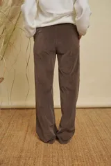 Pantalon de pana de corte recto y tiro alto, color marrón oscuro, con bolsillos laterales y cierre frontal.