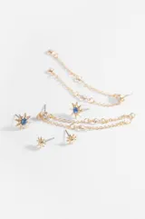 Set de tres pares de caravanas plateadas con diseño de estrella. Incluye un par pequeño, un par con piedra verde central y un par colgante con cadenas finas.