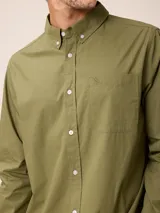 Camisa de manga larga en color blanco, confeccionada en algodón. Presenta cuello abotonado, cierre frontal con botones y un bolsillo en el pecho.