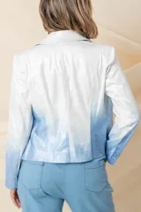 Chaqueta corta de cuero ecológico con diseño degradado de blanco a gris. Tiene cuello tipo solapa, cierre frontal asimétrico con broche y bolsillos con cierre.