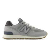 Championes urbanos New Balance modelo 574, color gris con detalles en azul marino. Confeccionados en una combinación de gamuza y malla, cuentan con el logo N característico en los laterales y entresuela con tecnología ENCAP para mayor amortiguación.