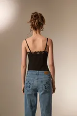 Body de breteles finos color blanco, con escote en V y detalle de encaje en el borde superior. Confeccionado en poliéster, presenta un diseño ajustado al cuerpo con cierre de broches en la parte inferior.