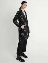 Tapado negro con estampado de texto en color blanco, cuello solapa y cierre frontal con un botón.