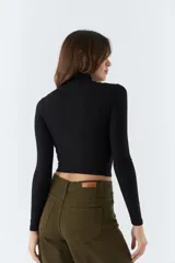 Polera negra de cuello alto y manga larga, de corte ajustado.