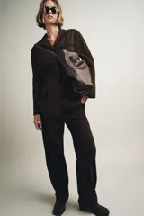 Blazer de mujer color marrón oscuro, confeccionado en piel de ante 100%. Presenta cuello solapa de muescas, manga larga, bolsillos de plastrón frontales y cierre frontal de botones.