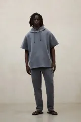 Buzo hoodie oversize de manga corta color gris, confeccionado en tejido tipo neopreno, con capucha ajustable mediante cordones y bolsillos delanteros diagonales.