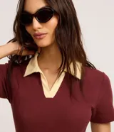 Blusa de manga corta confeccionada en tejido acanalado de algodón con elastano, de color bordó con cuello polo en tono amarillo claro y escote en V.
