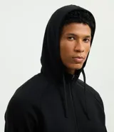 Saco deportivo con capucha y cierre frontal de cremallera, confeccionado en tejido tech fleece. Presenta mangas largas, bolsillos laterales con cierre y puños acanalados, ofreciendo un diseño liviano y térmico.