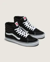Championes Vans modelo Sk8-Hi de caña alta, confeccionados en una combinación de lona y gamuza resistente. Presentan diseño clásico en color negro con la icónica banda lateral blanca, cordones blancos, puntera reforzada y suela de caucho tipo waffle para mayor agarre.