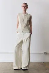 Blusa sin mangas de cuello redondo, confeccionada con detalles de encaje y puntilla a tono. Presenta cierre frontal con botones y diseño estructurado.