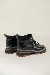 Borcego de cuero de estilo montañés con cordones, ganchos metálicos, suela track dentada en color suela y detalle de estrella lateral.