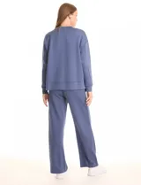 Buzo deportivo de cuello redondo, con hombros caídos y mangas largas con puños. Presenta costuras decorativas tipo pespunte en la parte frontal y en las mangas, con un diseño de ruedo recto y tajos laterales.