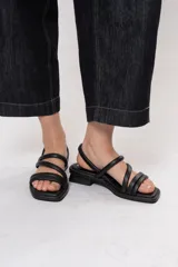 Sandalias negras de tacón bajo con múltiples tiras acolchadas, diseño de punta cuadrada y tira trasera ajustable.
