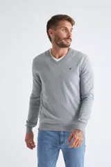 Sweater de tejido de punto color beige, con escote en V, mangas largas y puños y dobladillo acanalados. Presenta un pequeño logo bordado en el pecho.