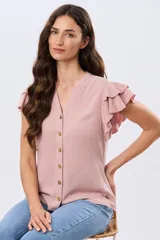 Camisa lisa color rosa, con cuello mao, escote en V y cierre frontal con botones de madera. Cuenta con mangas cortas decoradas con volados dobles.