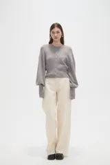 Saco de punto color beige, con cuello redondo, cierre frontal con botones y mangas largas con puños acanalados.