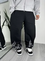 Jogging negro holgado de felpa, con diseño de llamas formadas por apliques de strass en los tobillos.