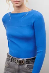 Buzo de morley color crema, con cuello bote y manga larga. Presenta un diseño de punto acanalado y un detalle de franja horizontal en el pecho.