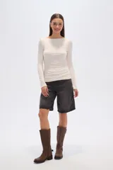 Top de manga larga ajustado al cuerpo, color beige claro, con escote bote y detalle de frunces drapeados en el torso.