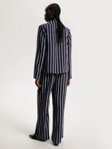 Blusa de poliéster azul marino con estampado de rayas verticales blancas. Tiene cuello abullonado y mangas largas.