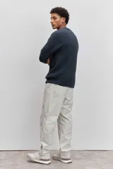 Sweater de tejido de punto acanalado en color marrón, con cuello redondo y ajuste holgado. Presenta un pequeño bordado distintivo en el pecho.